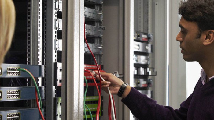 A student plugging in a network cable to a rank mounted networking unit