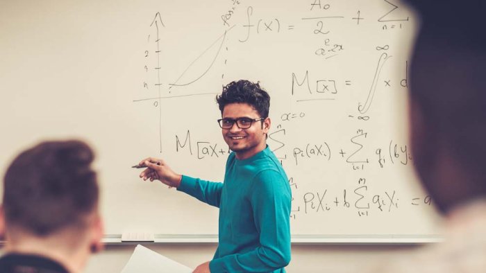 Lecturer demonstrating mathematical principles with equations on a whiteboard