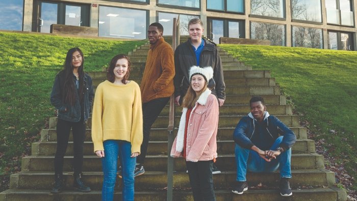 a group of students sitting and standing about a set of steps leading to a building