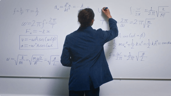 A lecturer writing mathematical equations on a whiteboard