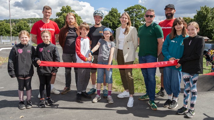 A group of people facing the camera, they are cutting a ribbon to open the Pump Track