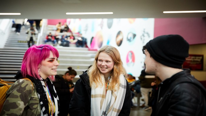 A group of three students stood talking