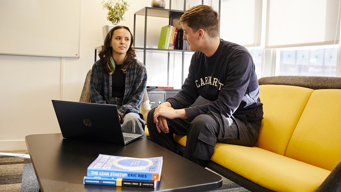 Male and Female meeting in the University's Enterprise Centre, with a laptop and business start up books on the table in front of them