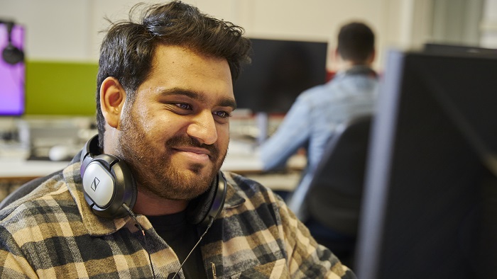 Male student sat in front of a computer screen