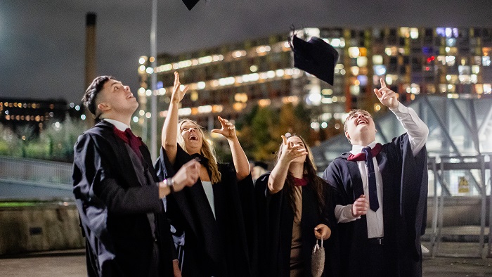 Graduates celebrating, throwing their mortarboards in the air