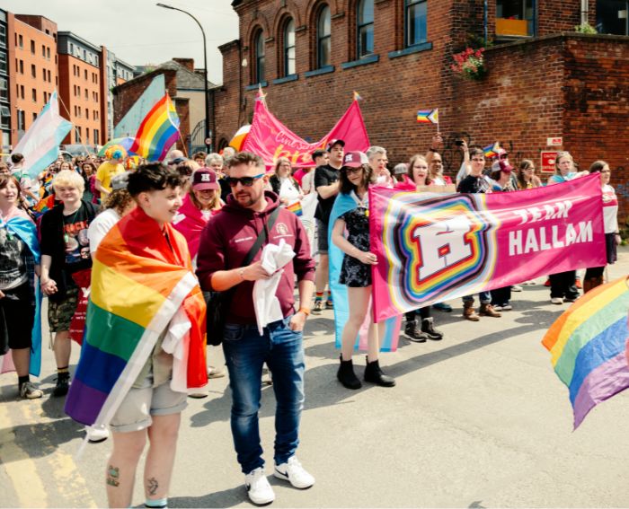 A group of people holding a banner up at Sheffield Pride celebration 