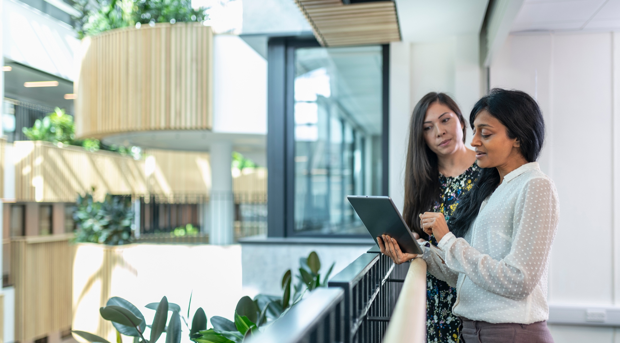 two people looking at a tablet in a brightly lit atrium