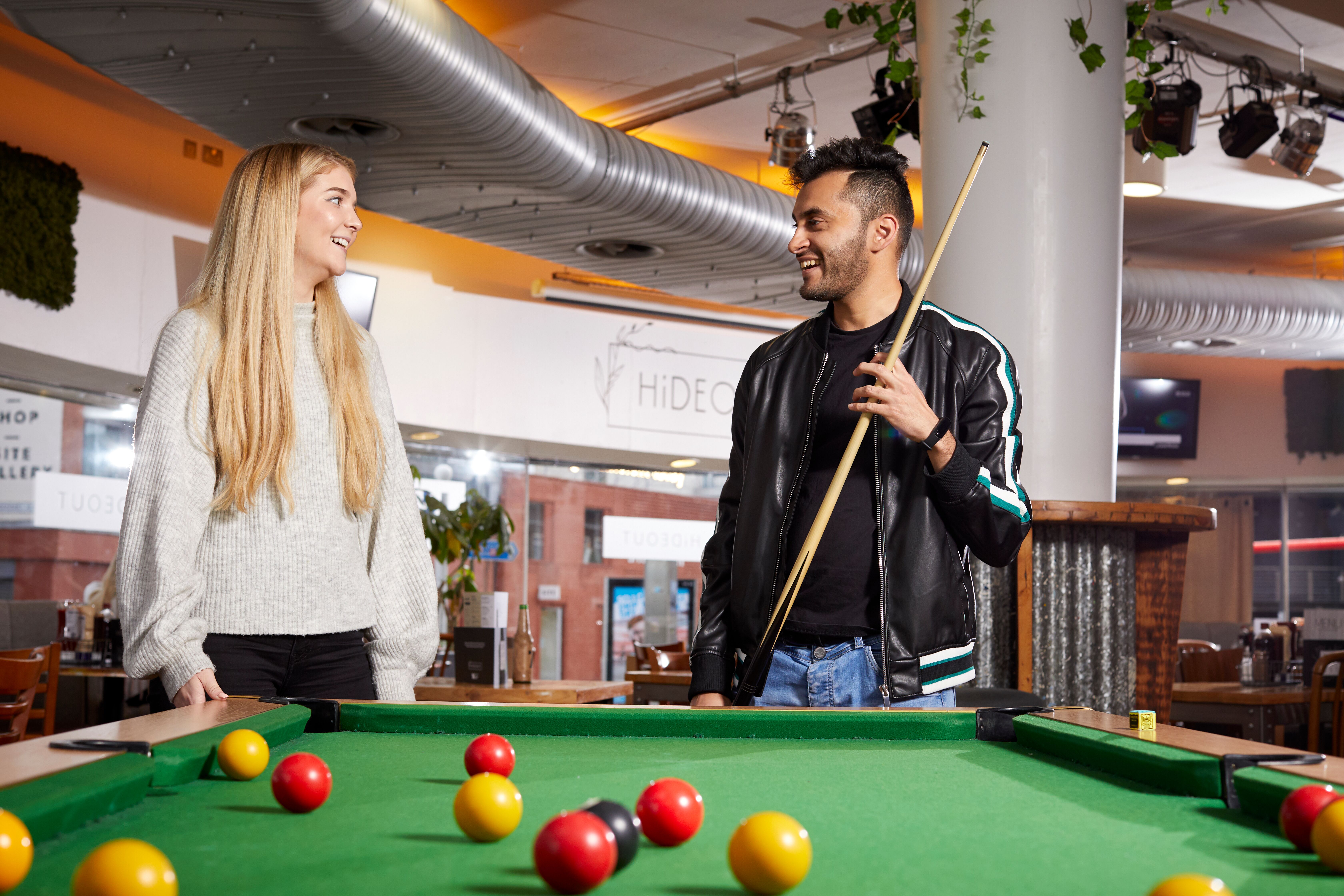 Two people talking while playing pool