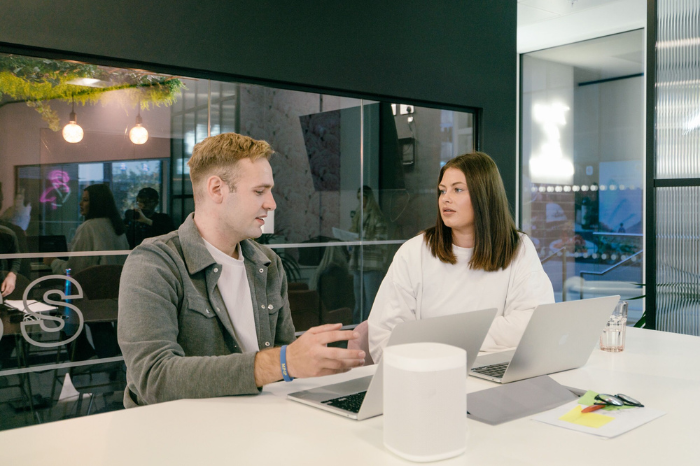 Two people talking over laptops