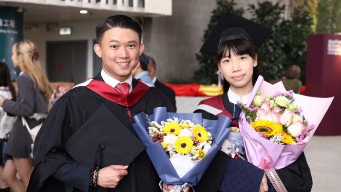 Two students graduating holding bunches of flowers