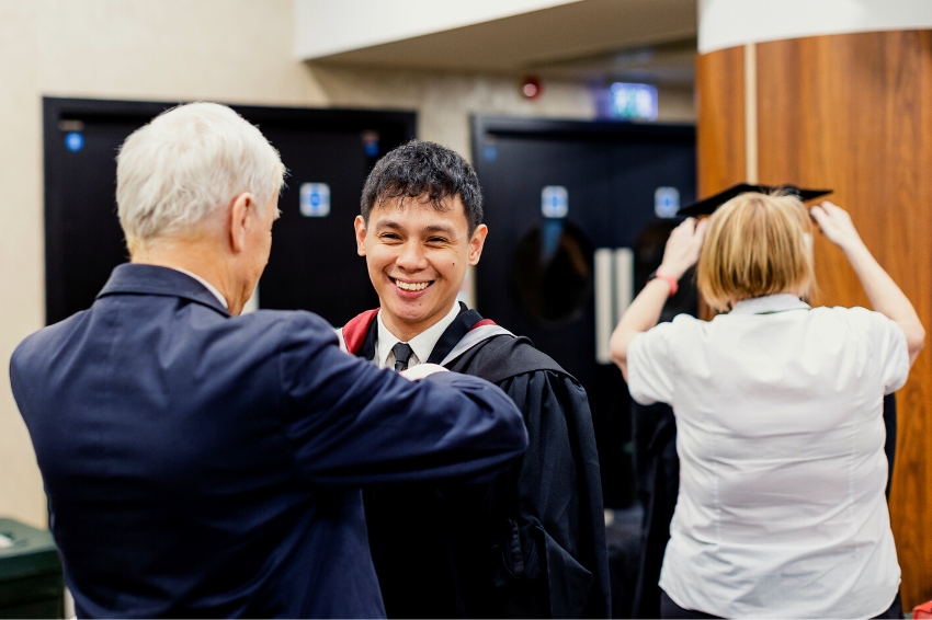 smiling graduate getting fitted for graduation gown