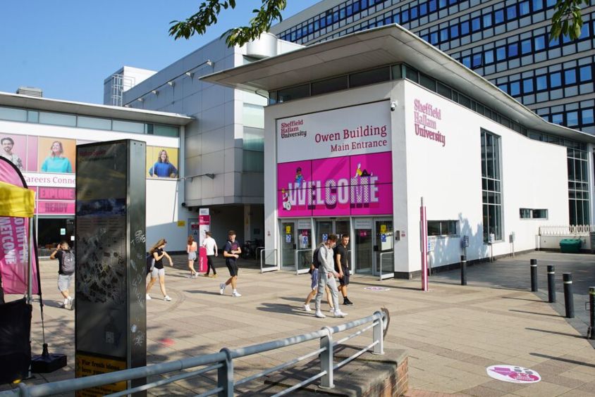 Several students walking through Hallam Square on a sunny day. A large welcome banner is on display in the entrance.