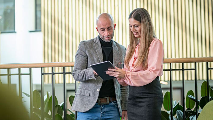 Two people looking at a tablet computer together in a bright office interior