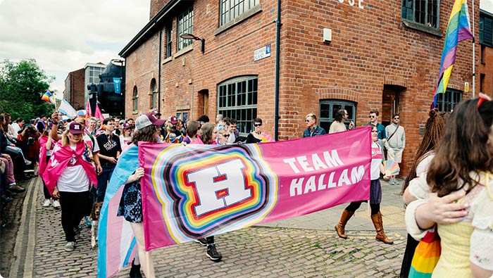 Pride march at Kelham Island in Sheffield. The crowd is carrying a 'Team Hallam' banner.