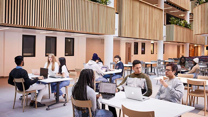 Groups of people relaxing around tables in a bright atrium space