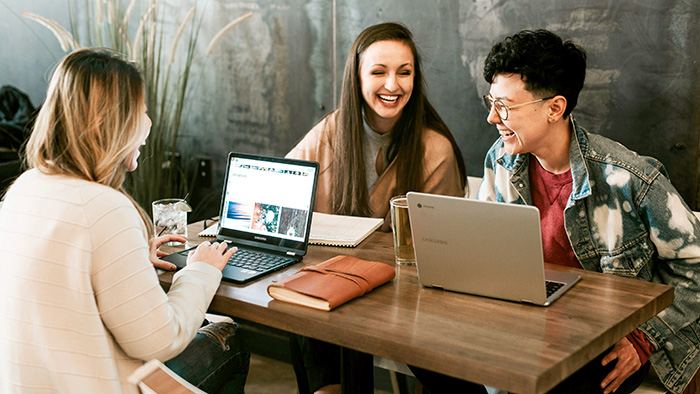 Three cheerful students working together at a table.