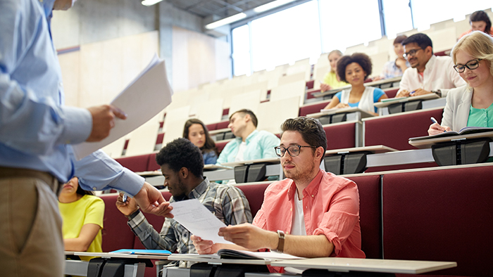 A lecturer handing papers back to a class of students