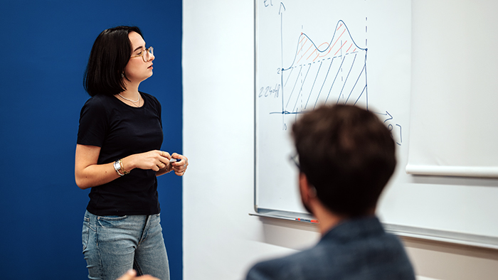 A student giving a presentation in a small classroom.