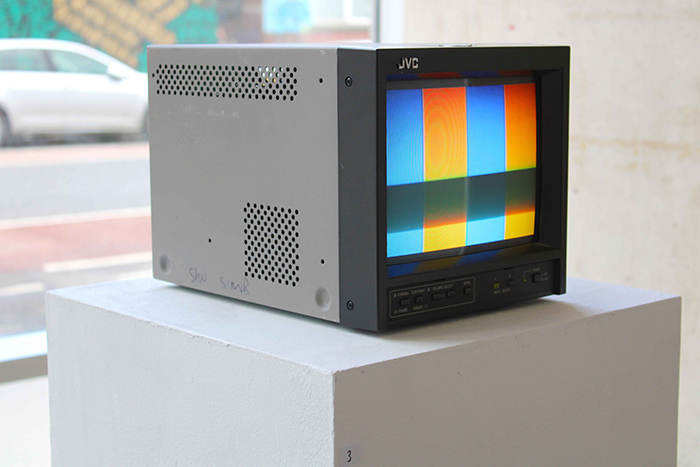 A retro TV installation, with the screen showing a rainbow static.