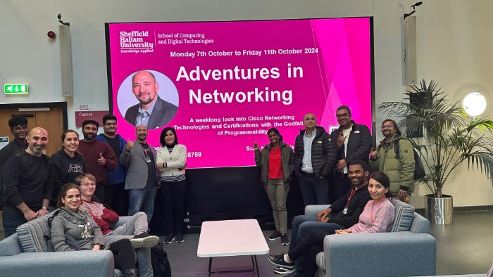 Photo of event attendees in front of event poster.