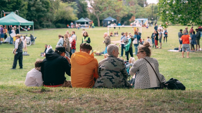 Group of people sitting on a grassy area in a park 