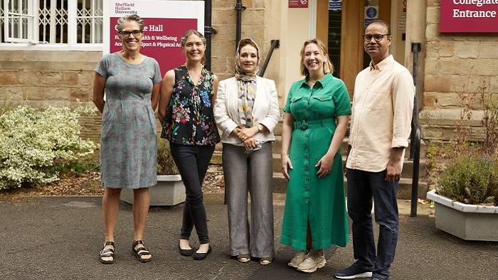 Four women and a man stood outside a stone building with Sheffield Hallam University signs 