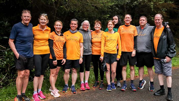 A mixed group of people posing for a photograph at a parkrun event