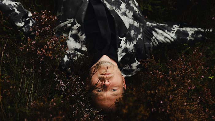 Portrait of Dr Tom Payne lying on moorland surrounded by heather plants