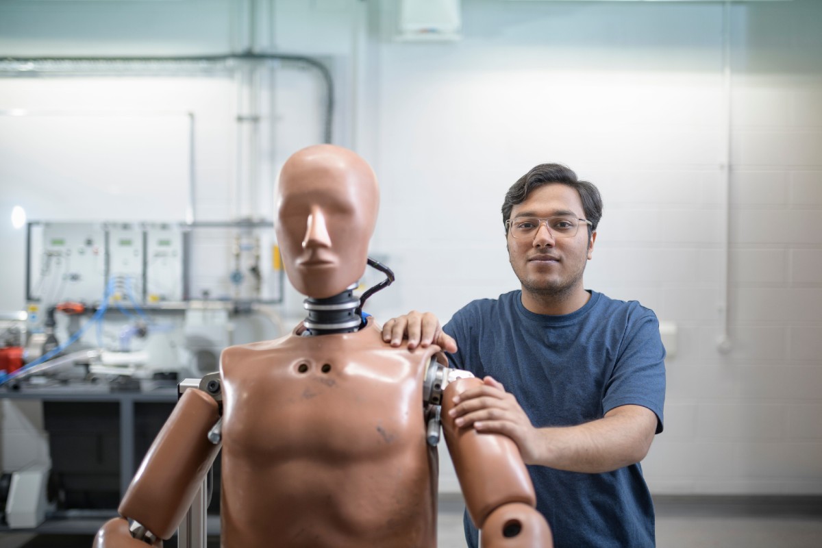 Student standing with a crash test dummy