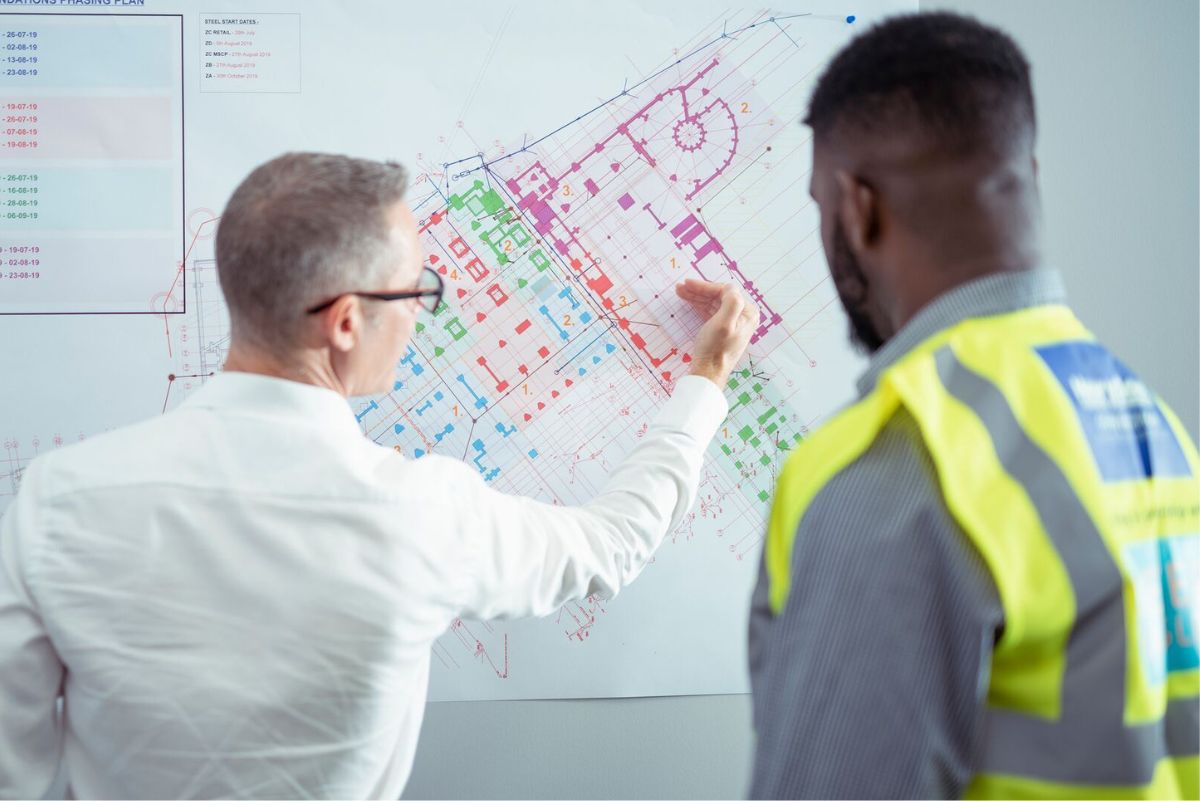 A student and lecturer looking at a board displaying plans