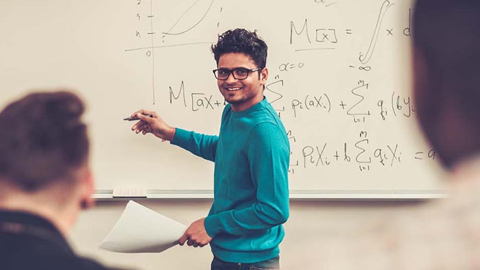 A student writng equations on a whiteboard