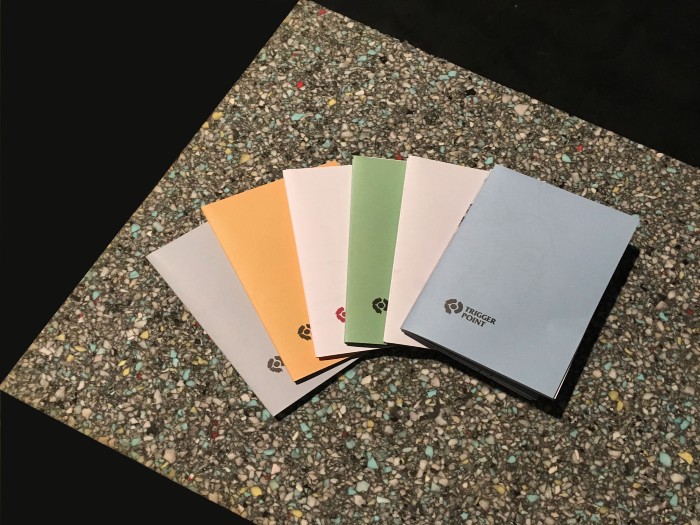 A series of Trigger Point booklets on a pebbled surface