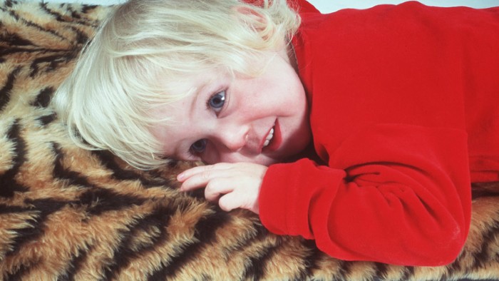 Toddler lying on their front on a furry tiger skin blanket