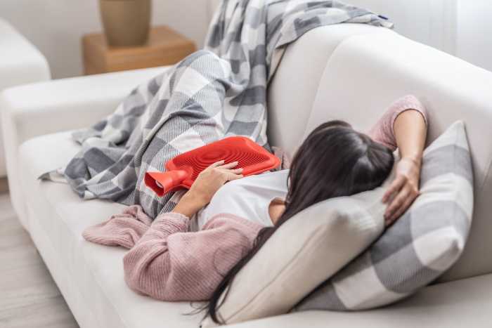 woman lying on sofa with hot water bottle