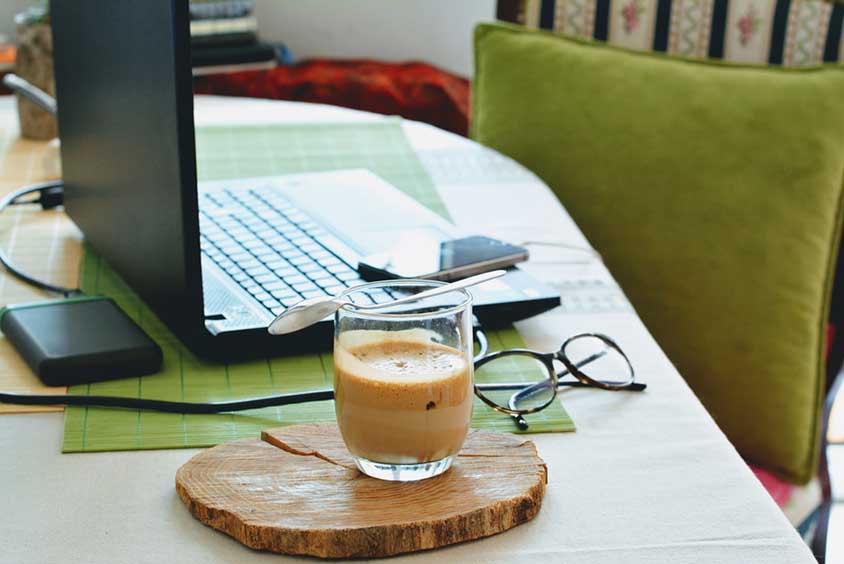 Laptop, phone and half-full coffee cup on a table