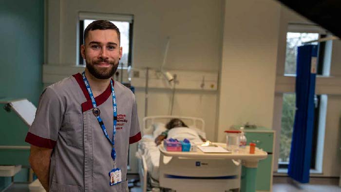 Male nursing student smiling on a ward