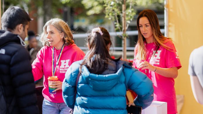 2 members of staff speaking to students in the Welcome stand