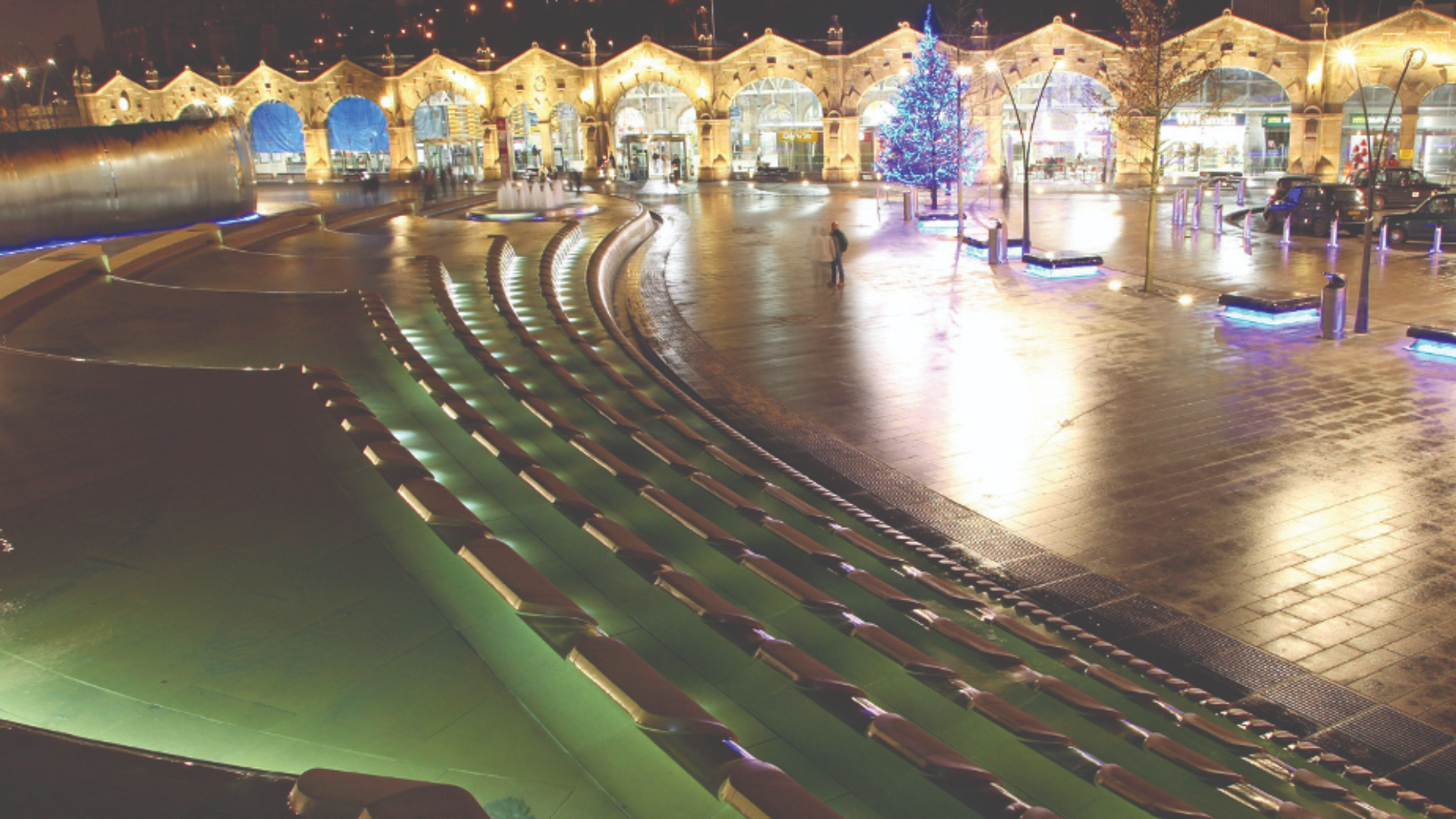 Sheffield train station, fountains and Christmas tree lit up in the evening in Winter